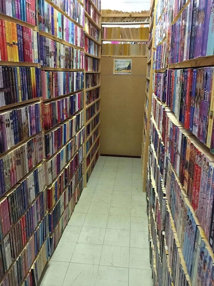 Narrow aisle in a bookstore lined with bookshelves packed with books.