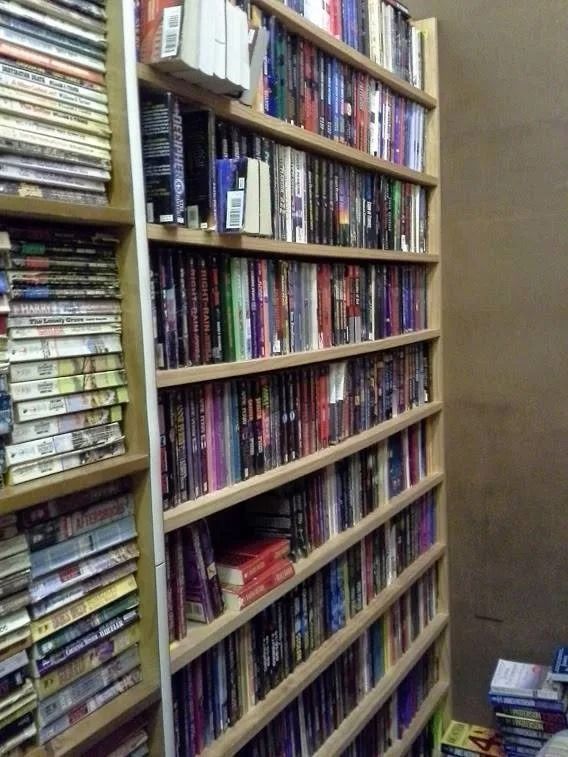 Bookshelves filled with books, partially obscured by another bookshelf to the left.