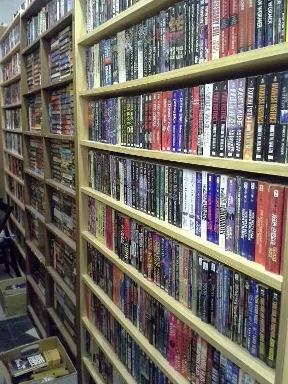 Bookshelves filled with books, varying colors and sizes, in a room.