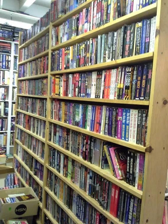 Wooden shelves packed with DVDs in a store, bright lighting.