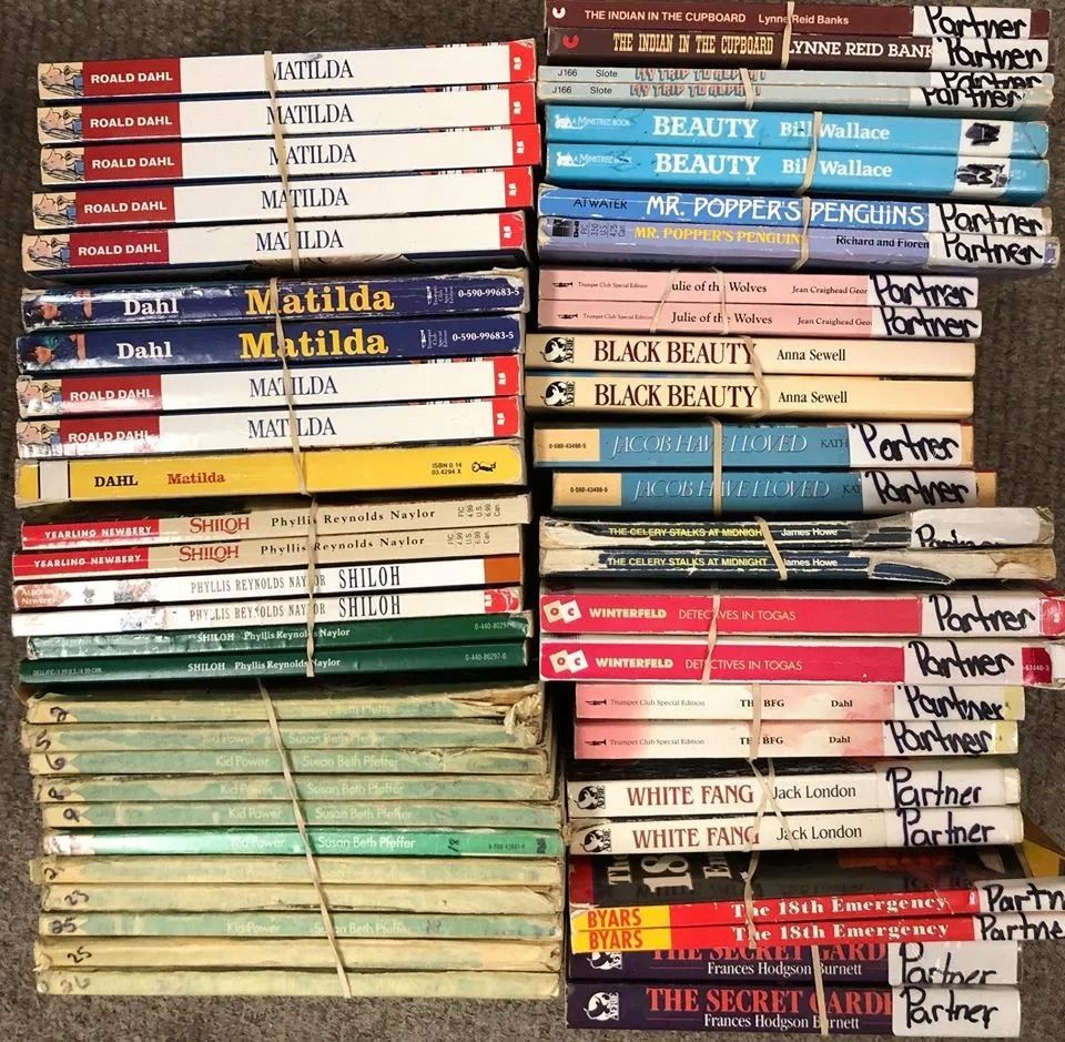 Stacks of aged books tied with rubber bands. Titles include 