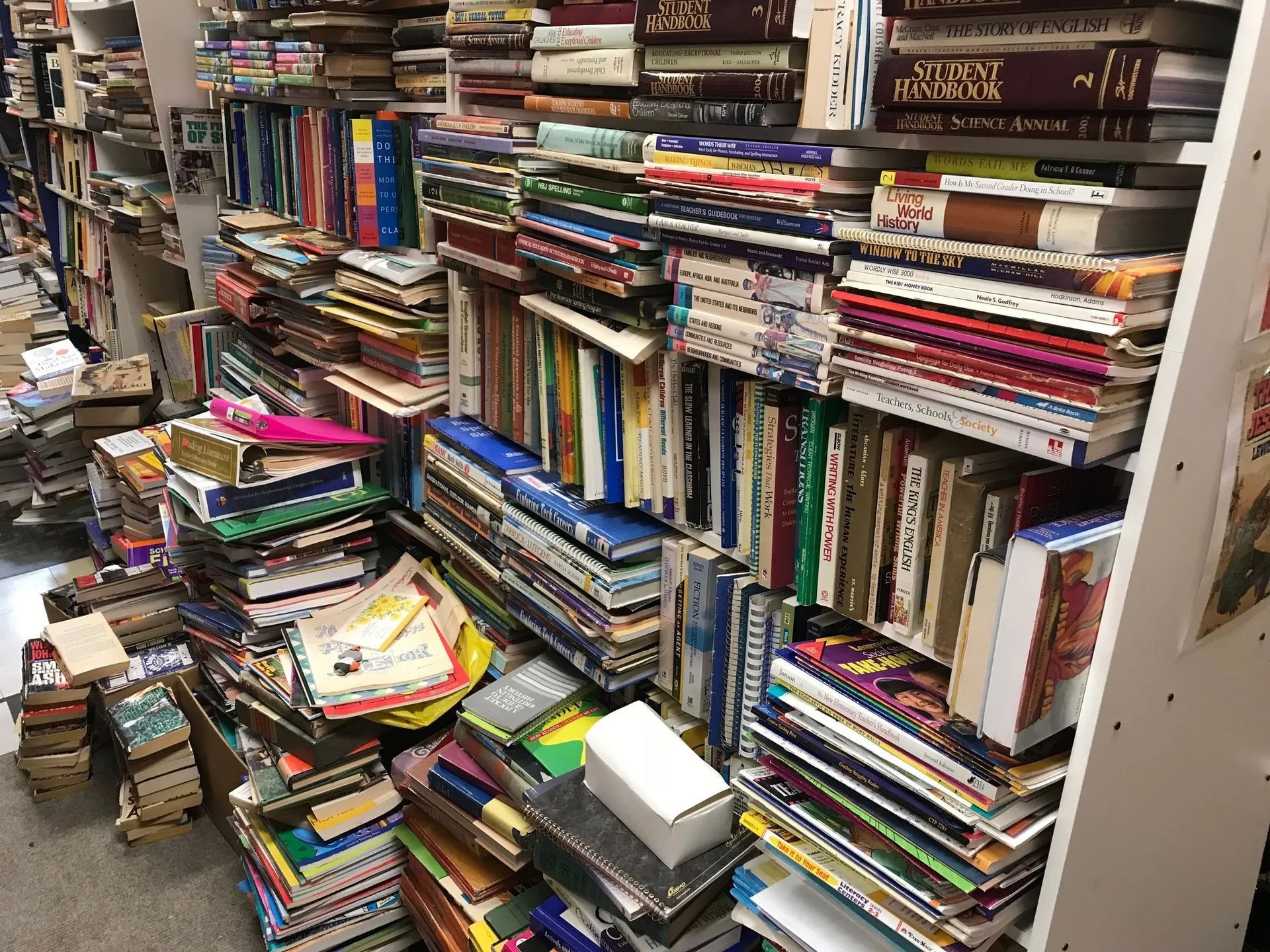 Books piled haphazardly on shelves in a cluttered bookstore.