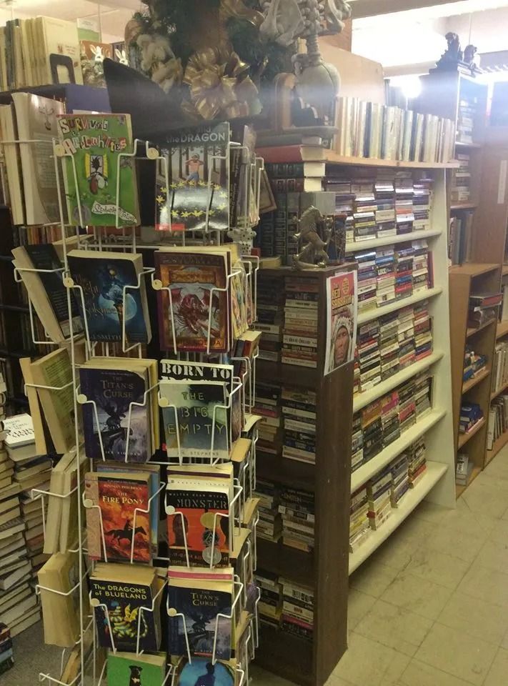 Bookshelves in a bookstore, with a wire rack of books in front.