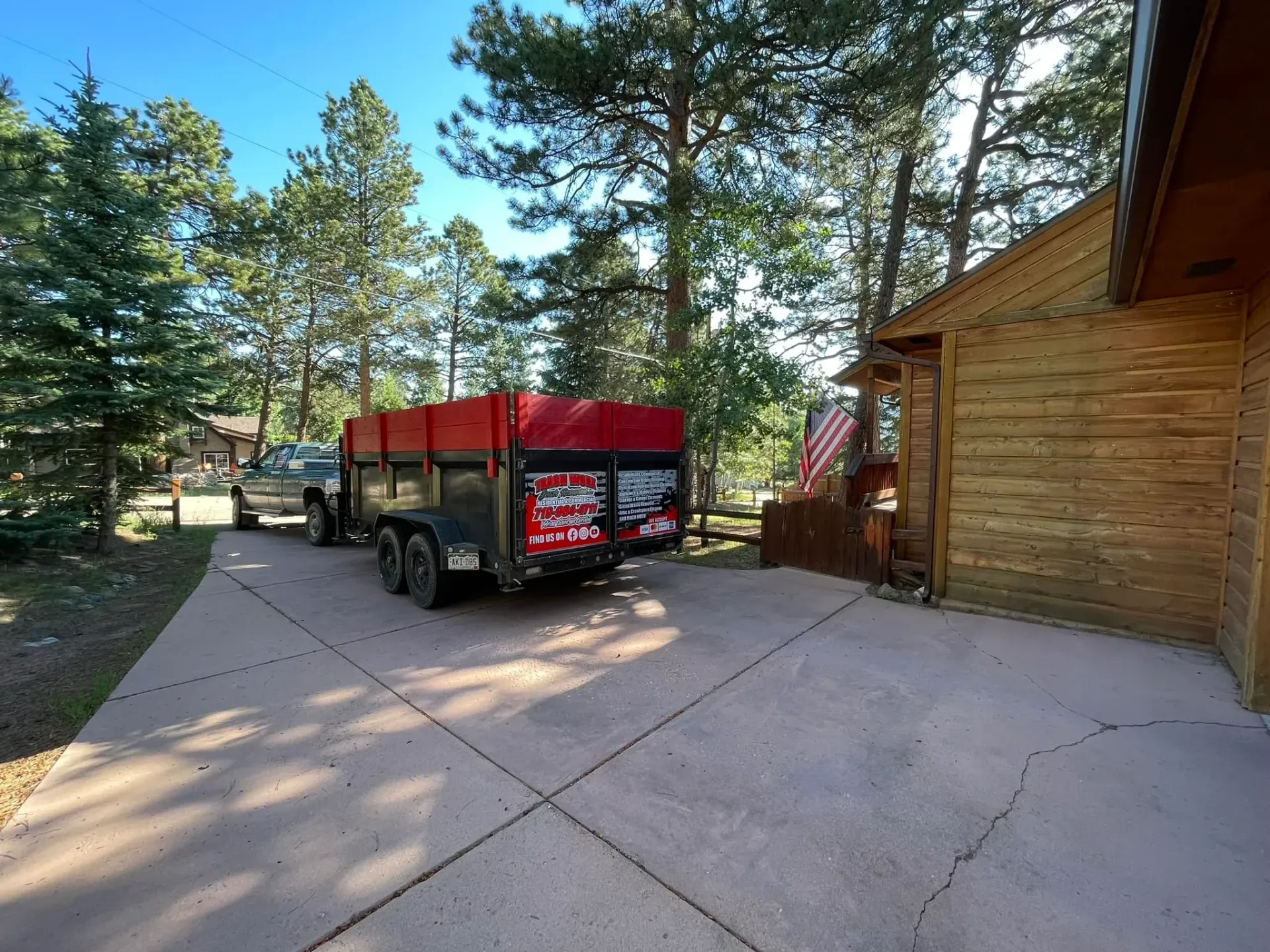 A dumpster is parked in a driveway next to a house.