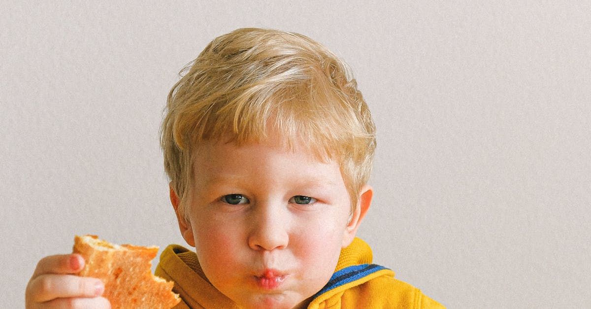 A young boy is eating a piece of bread.