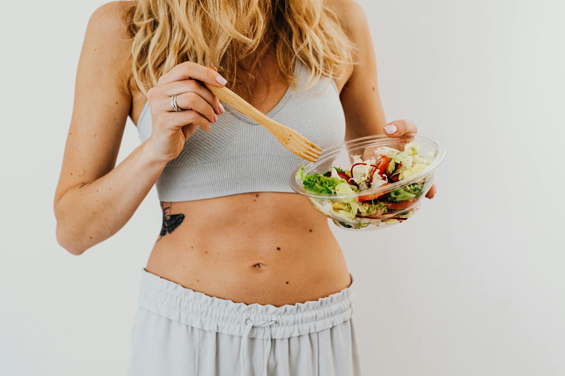 A woman is eating a salad with a fork from a bowl.