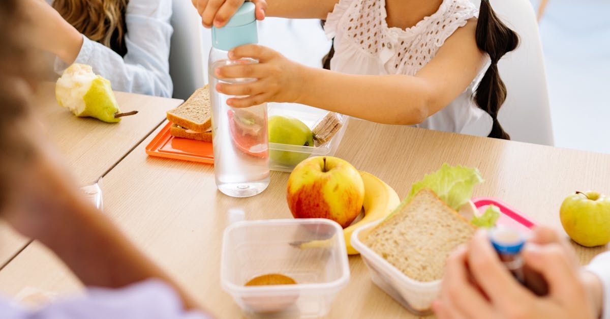 A group of children are sitting at a table eating lunch.