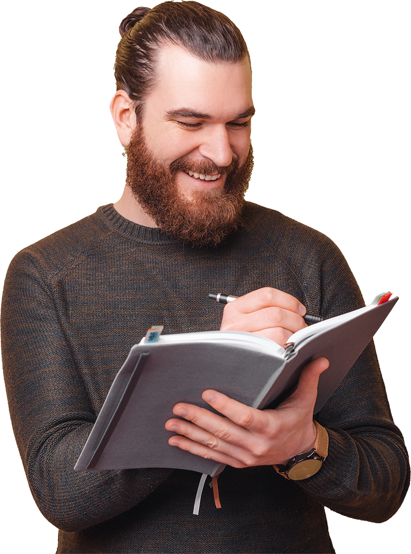 man with manbun writing on notebook