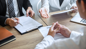 Business meeting with people taking notes and discussing documents at a table