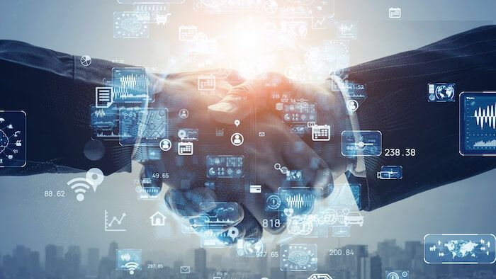 Two men shaking hands with an A and electronics look in the background.