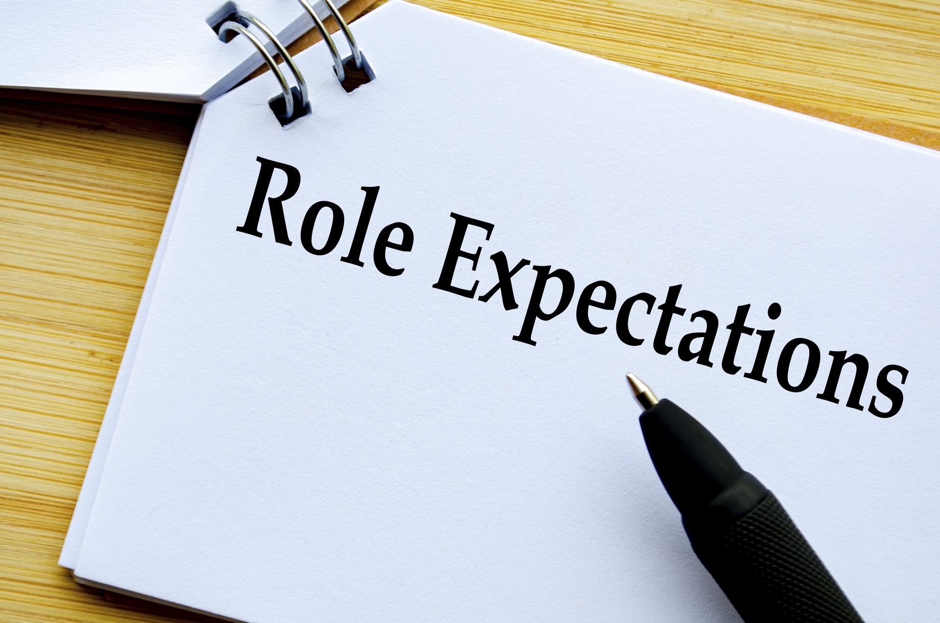 The words “Role Expectations” written on a clip board with a pen nearby.