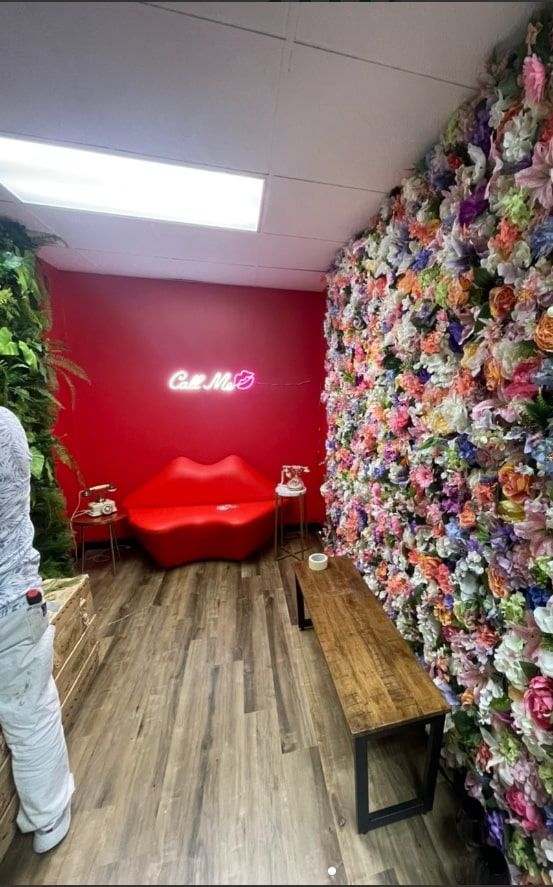 A room with a red couch and a wall of flowers.