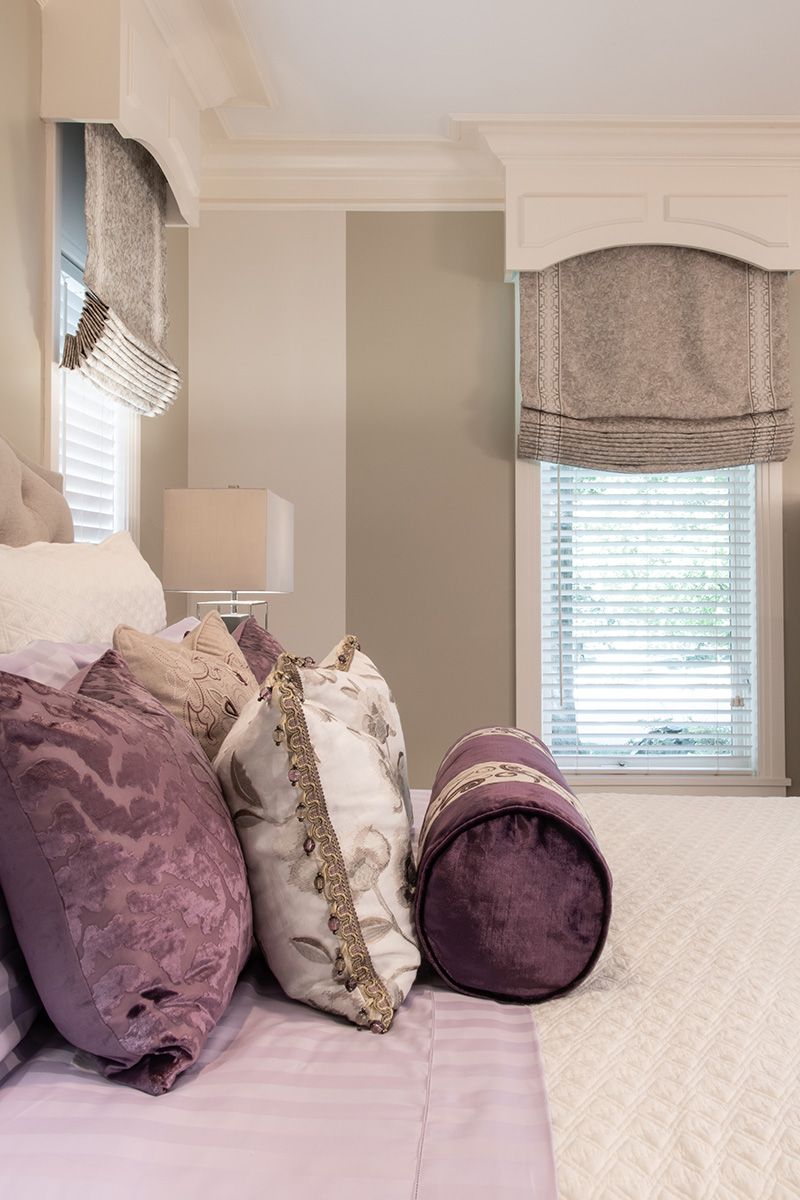 A bed with purple pillows and a window in a bedroom.