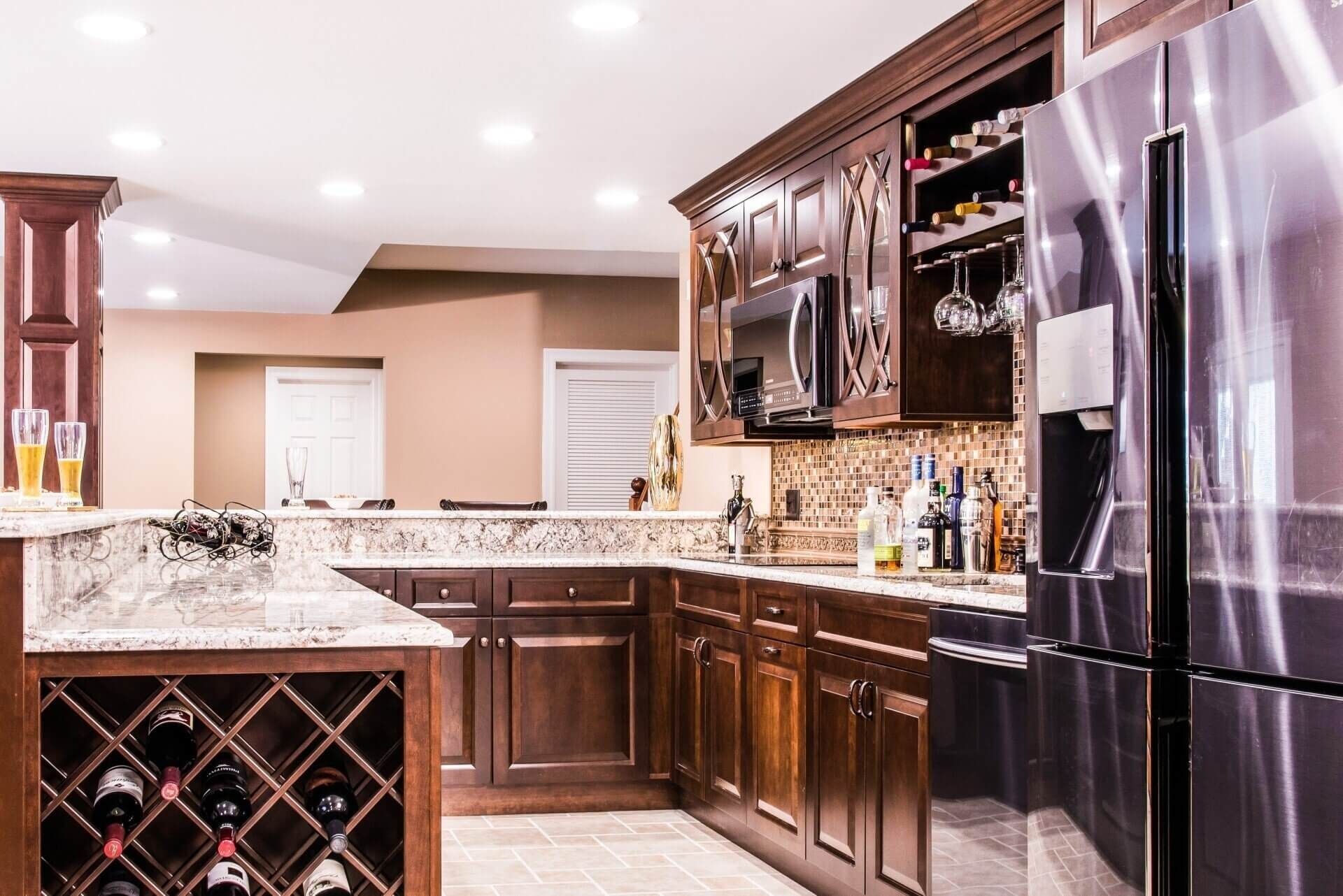 A kitchen with stainless steel appliances , wooden cabinets , granite counter tops and a wine rack.