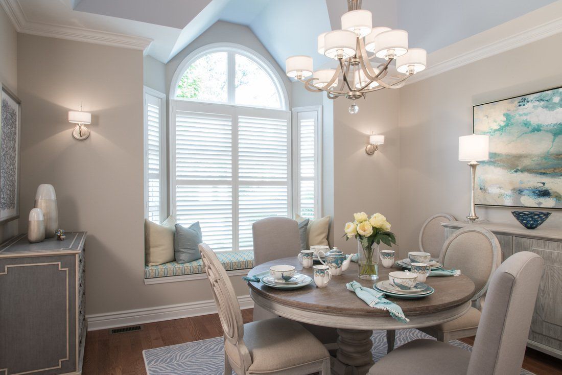 A dining room with a round table and chairs and a chandelier.