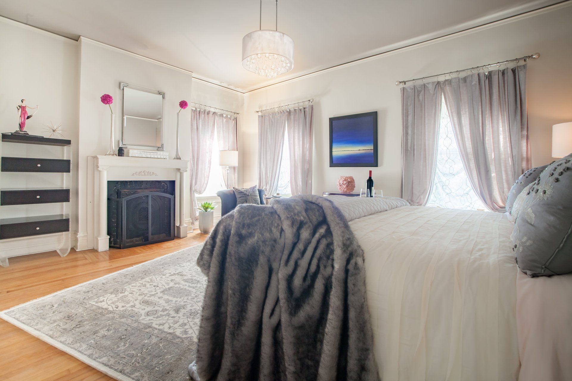 A bedroom with a king size bed , fireplace , and a rug.
