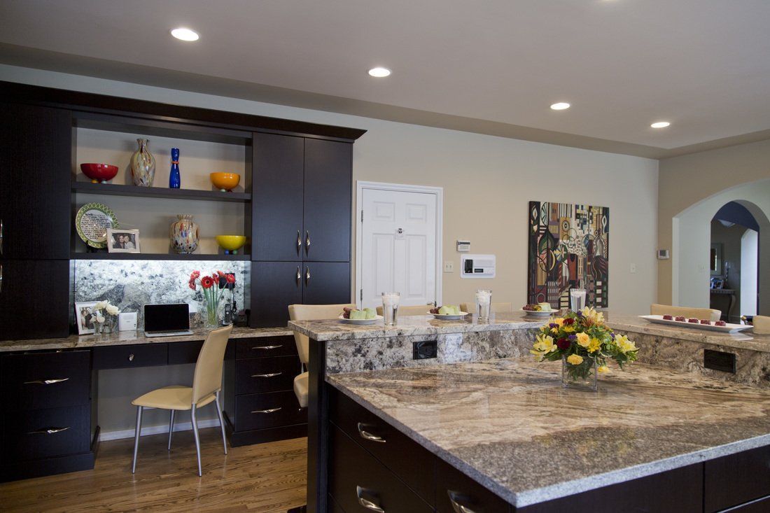 A kitchen with a large island and a desk with a laptop on it.