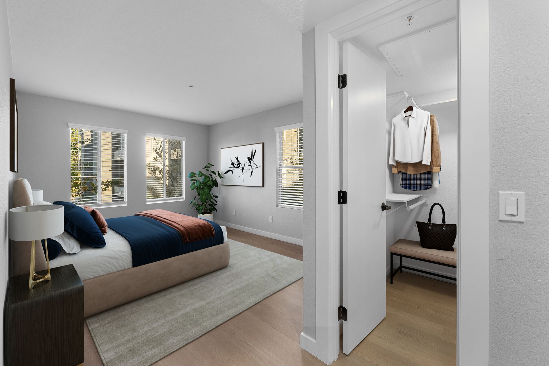 Bedroom with a bed, closet, and windows. Light walls, wood floor, neutral colors.