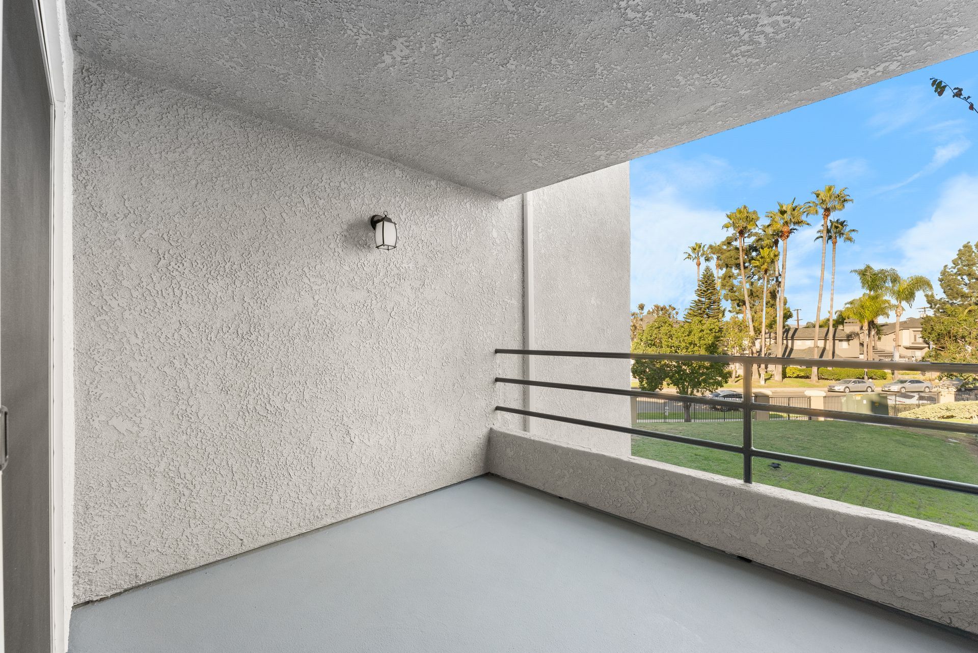 An empty balcony with a railing and a view of a grass field.