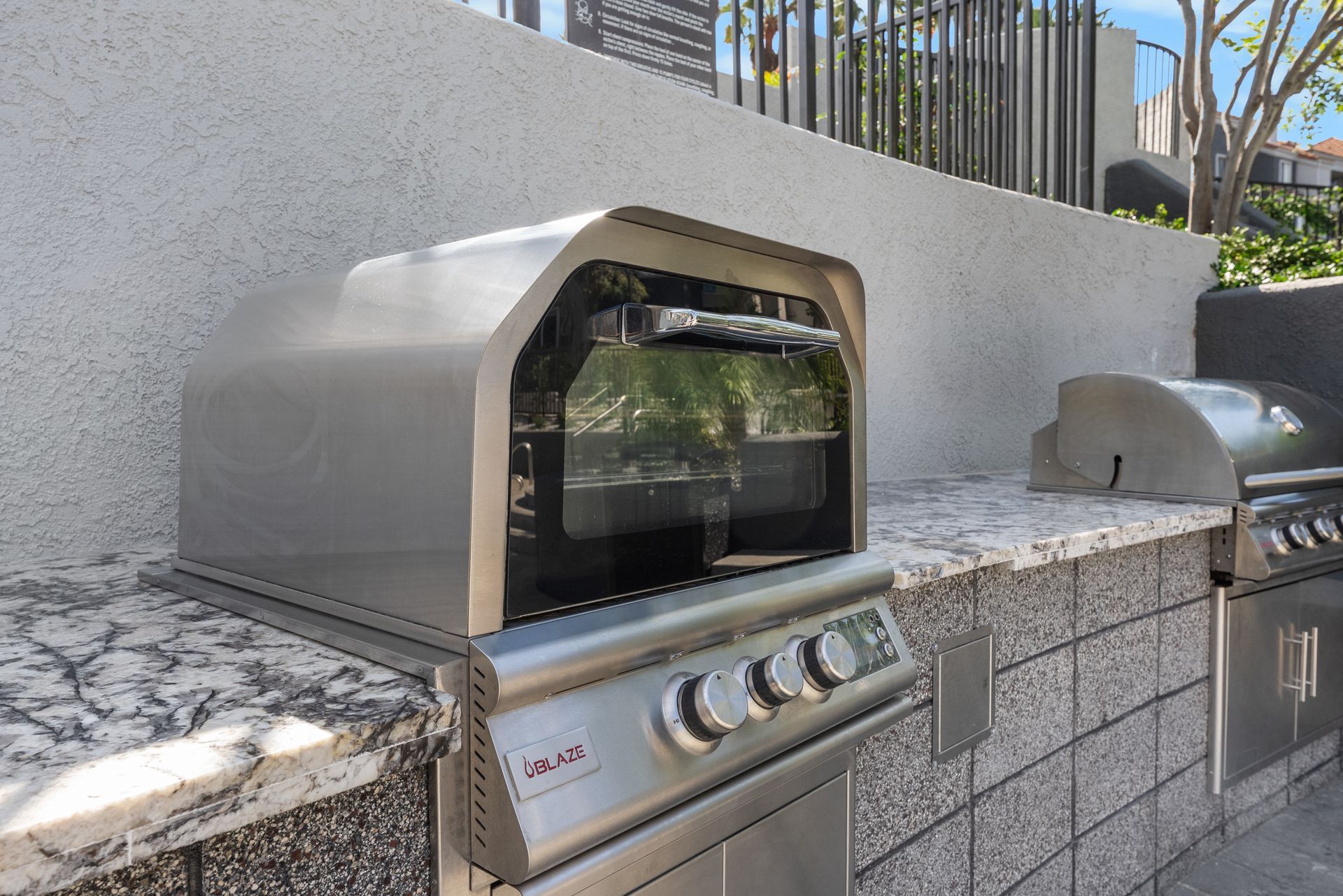 Stainless steel outdoor pizza oven with cover on granite countertop.