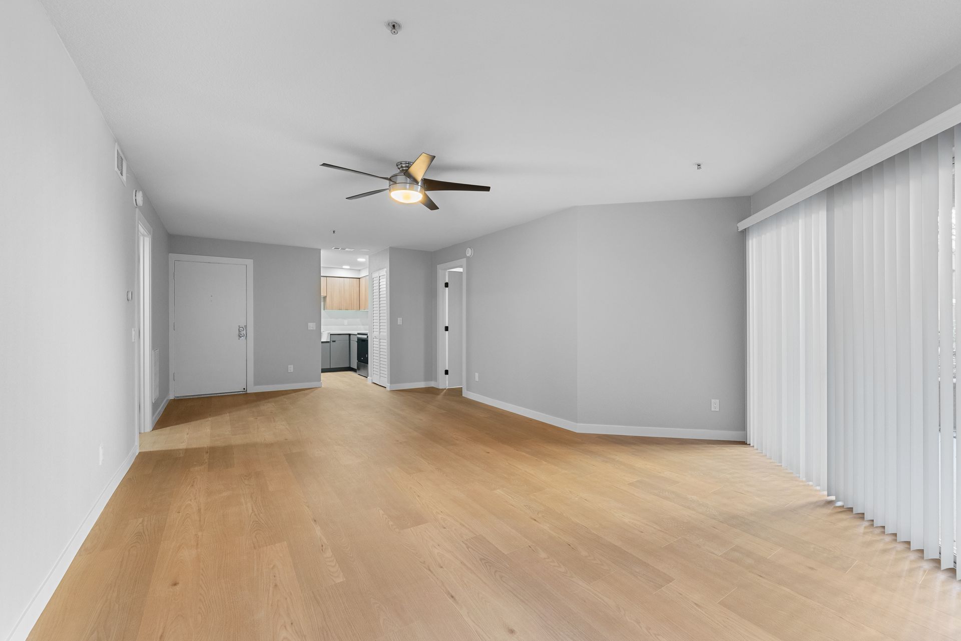 An empty living room with hardwood floors and a ceiling fan.