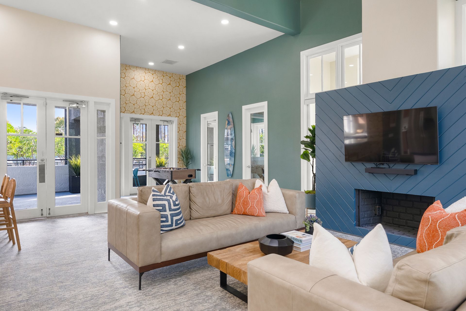 Living room with beige couches, fireplace, TV, and outdoor access.