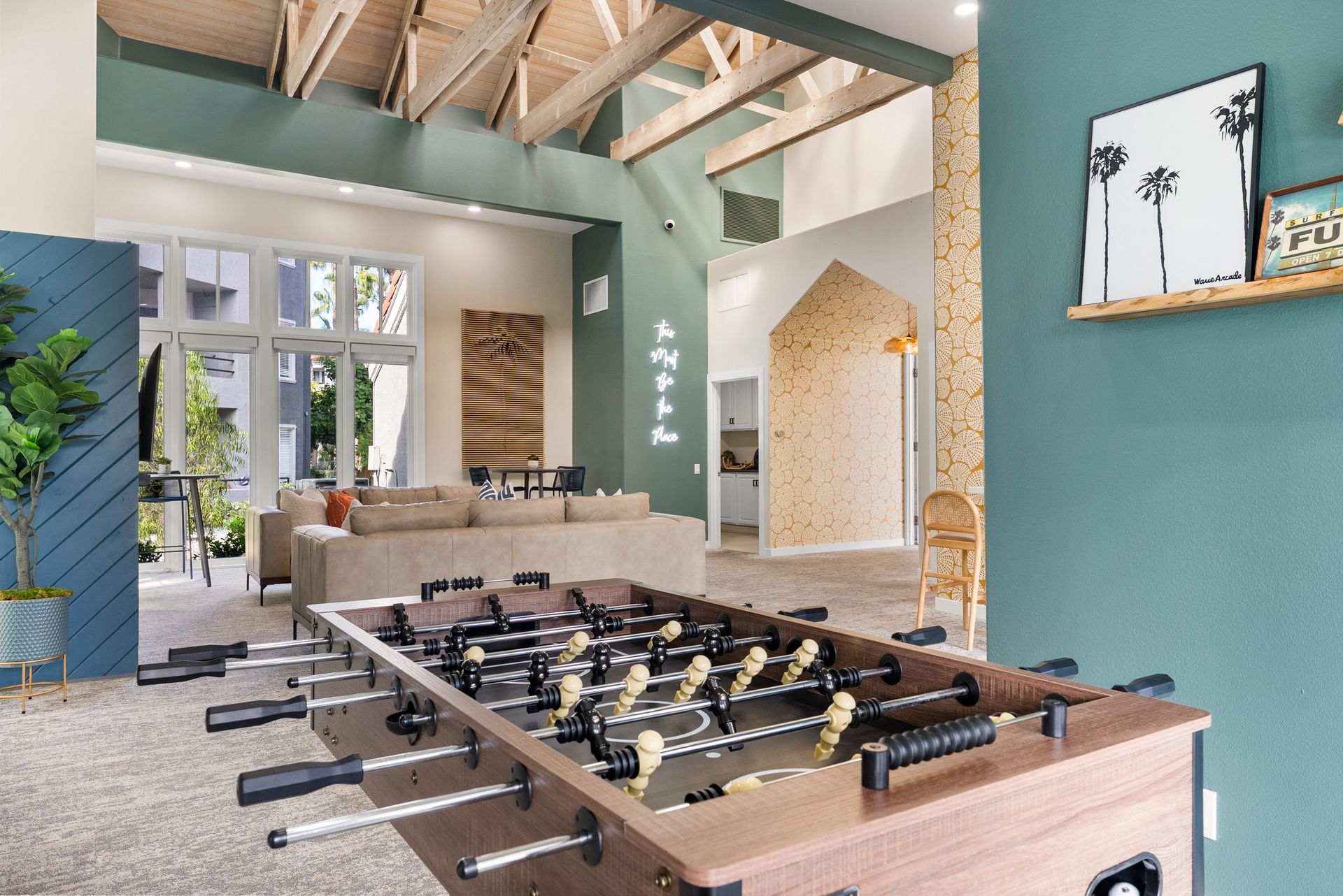 Foosball table in a modern rec room with a high ceiling, and a large sofa visible in the background.