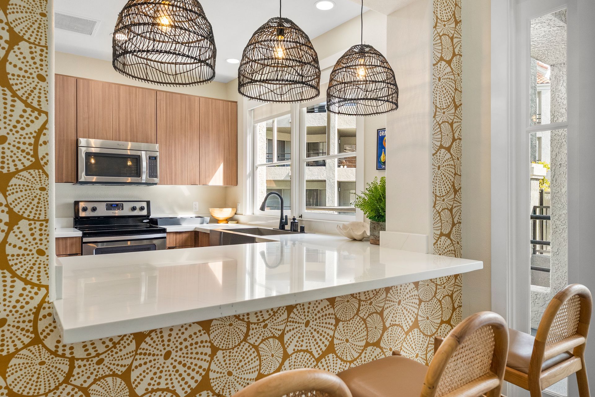 Kitchen with light countertops, wood cabinets, and woven pendant lights.