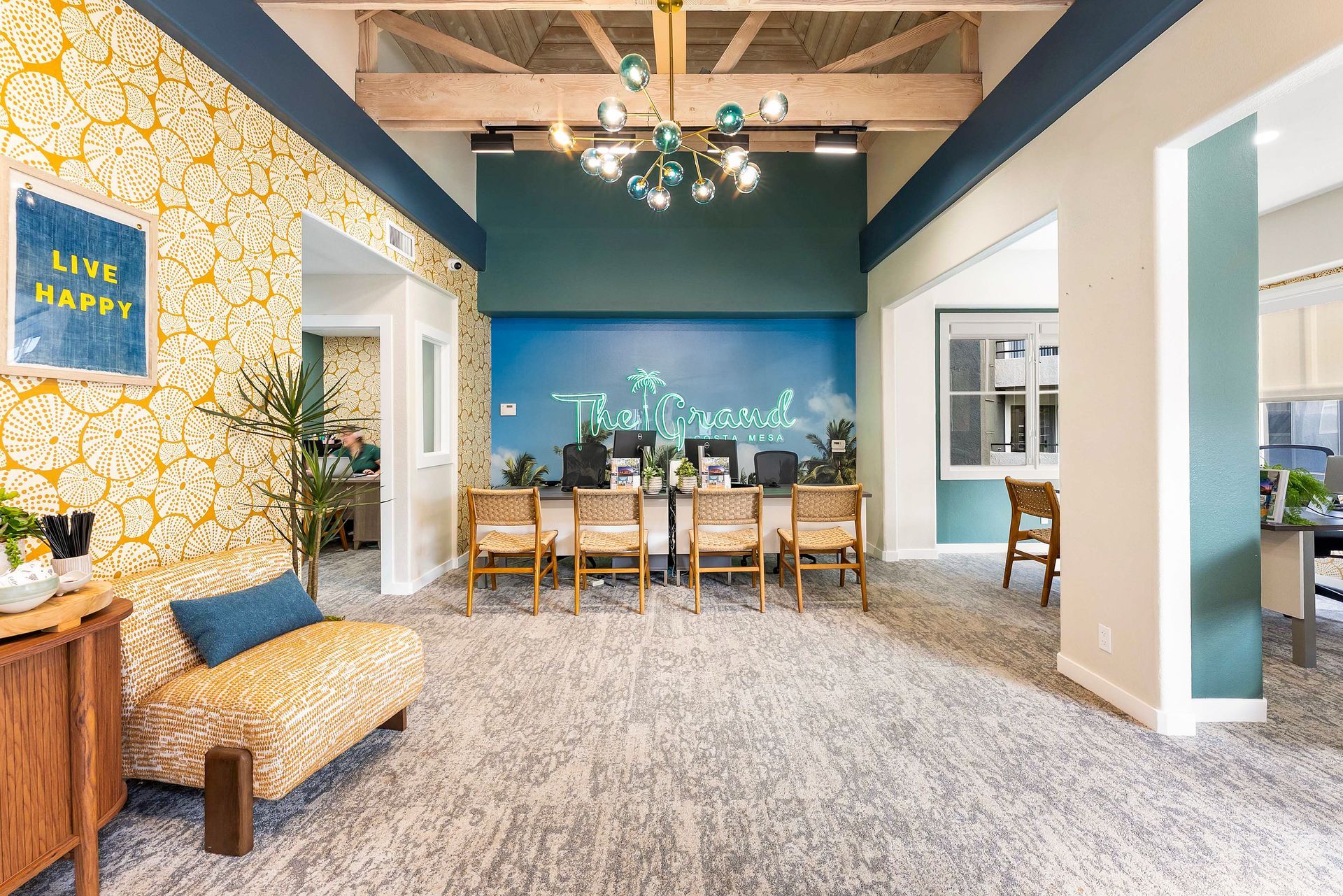 Reception area with teal accent wall, desks, wicker chairs, and patterned wallpaper.