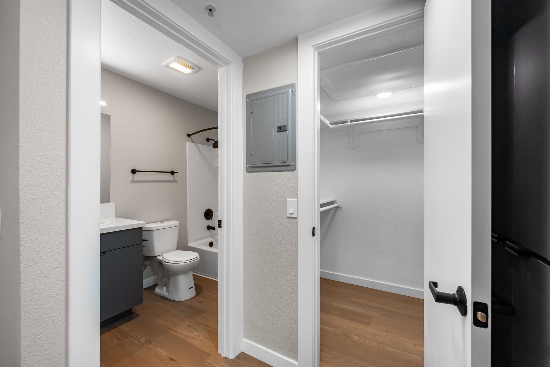 View of an open door to a bathroom and a closet in a home. The door is framed with white trim.