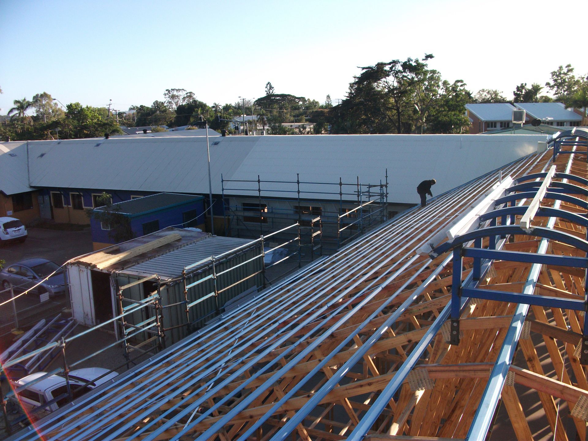 Red Corrugated Roof With Chimney Against a Bright Blue Sky With Wispy Clouds — Roof 4 U in Burdell, QLD