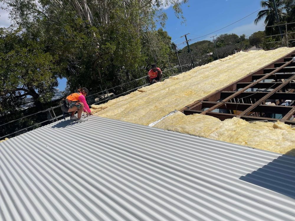 Workers Installing Insulation on a Corrugated Metal Roof. Trees and Sky in the Background — Roof 4 U in Alice River, QLD