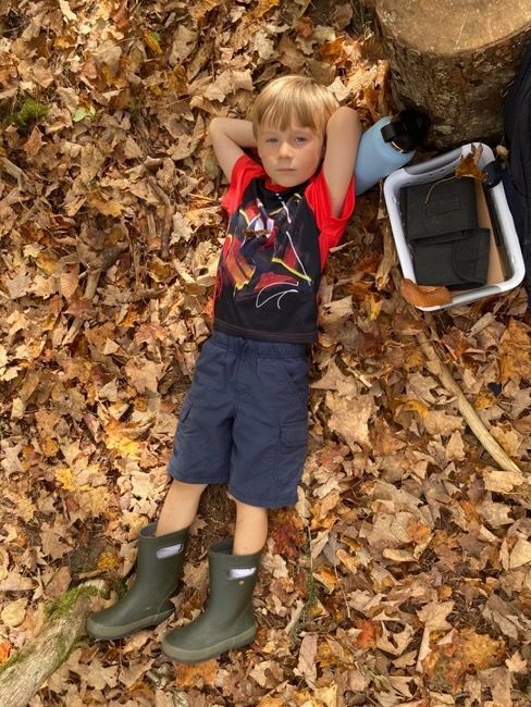 A preschool relaxing on the ground in gumboots