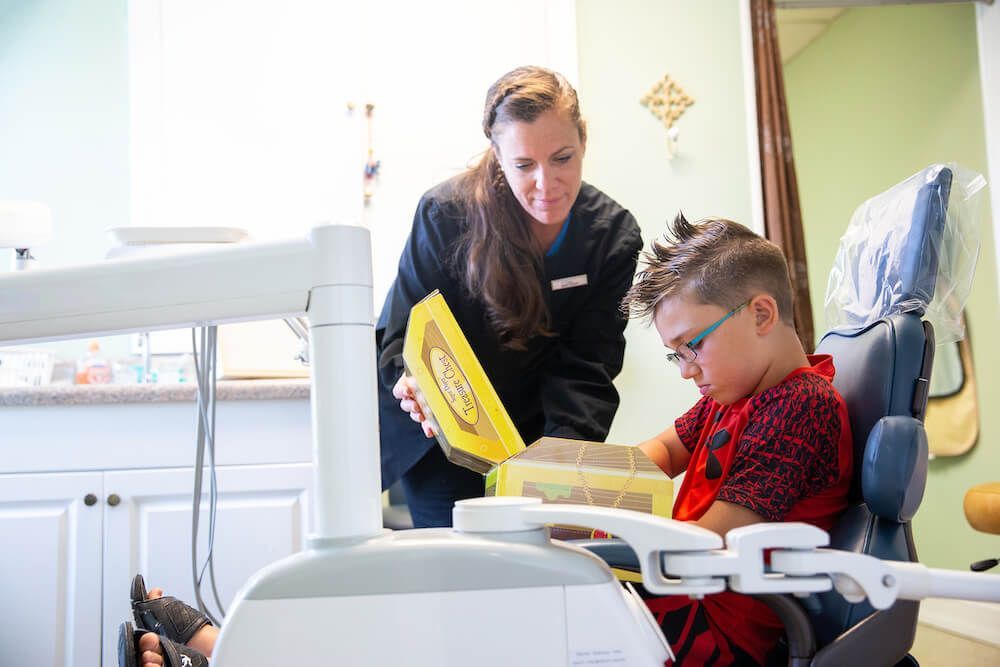 A woman is standing next to a young boy in a dental chair.