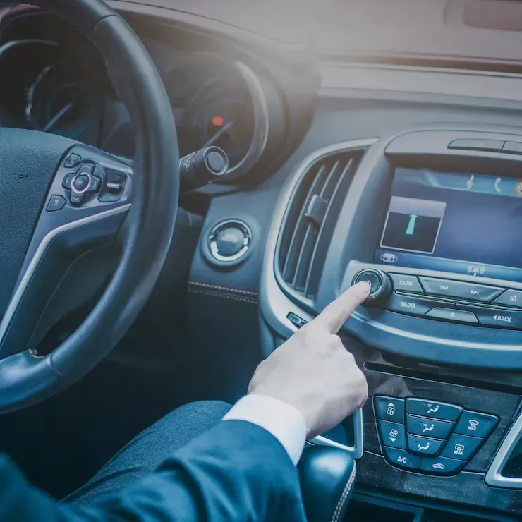A mechanic works on a car engine while using a red refrigerant service machine in an auto shop.