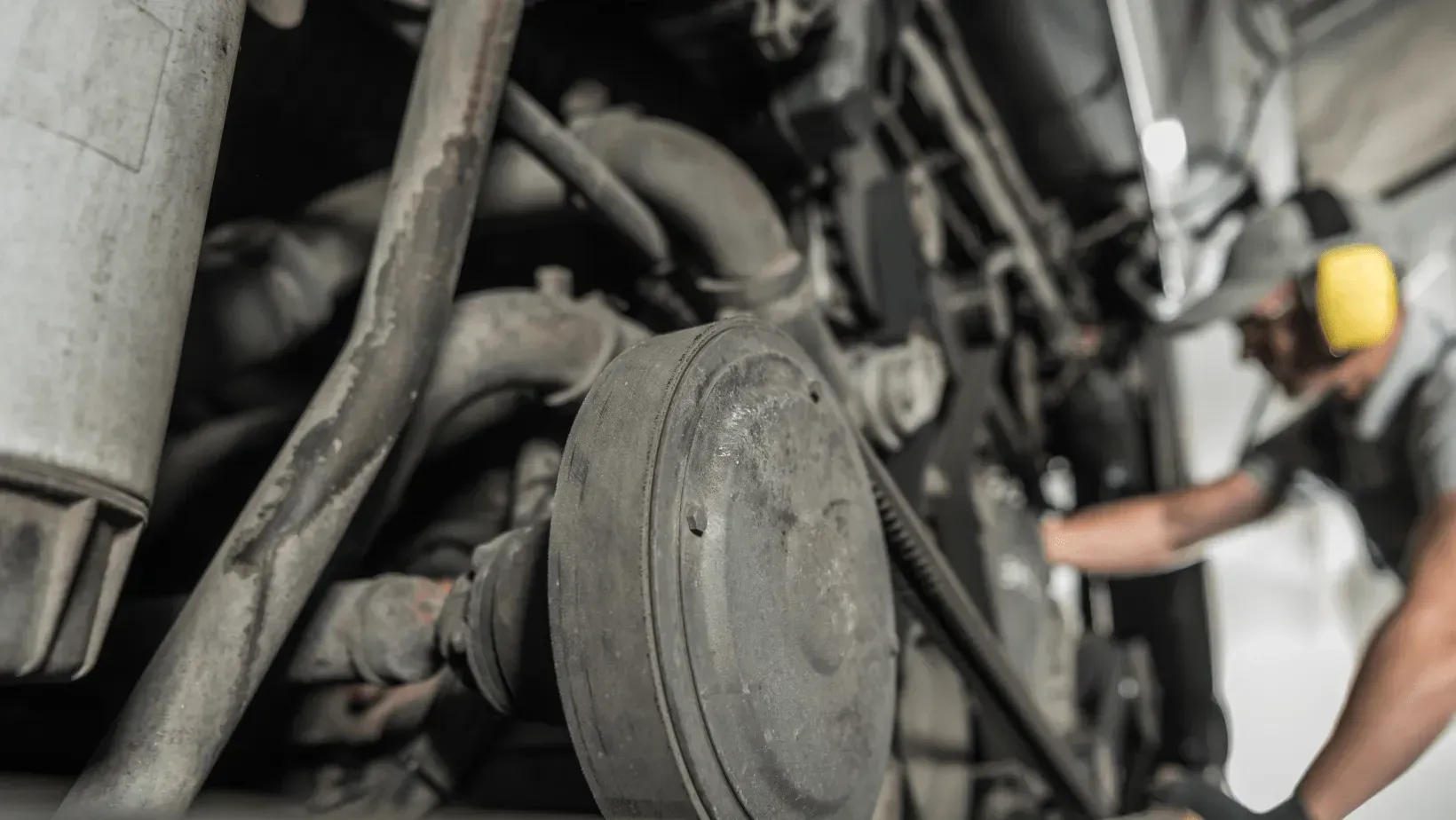 A smiling person holding a yellow mug stands in the open doorway of a white camper parked in a wooded area.