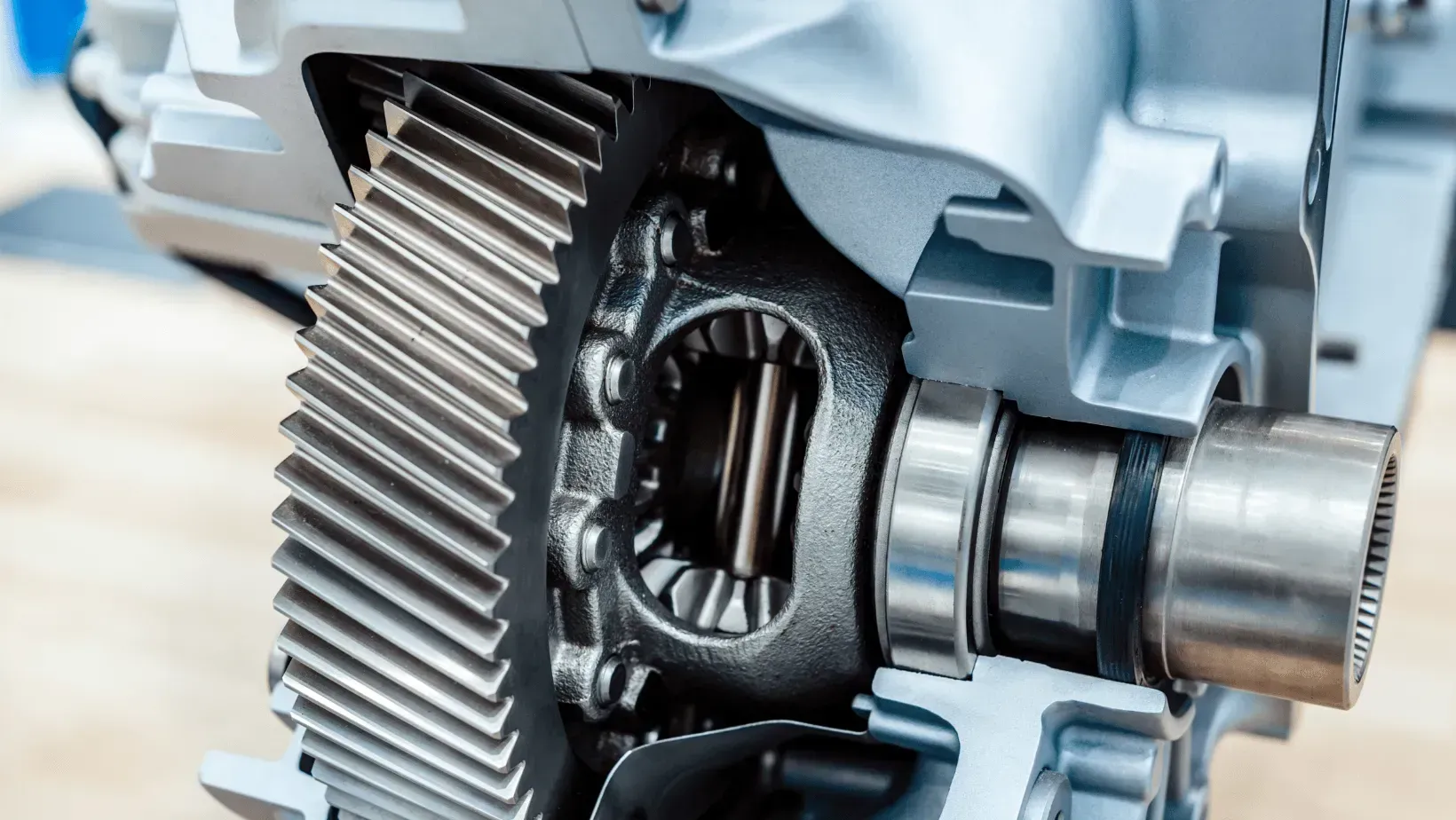 Two mechanics in work uniforms discuss repairs while standing before an open car hood in a garage.