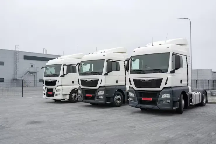 A mechanic wearing gloves and overalls uses a wrench to work on a car's brake drum in an auto repair shop.
