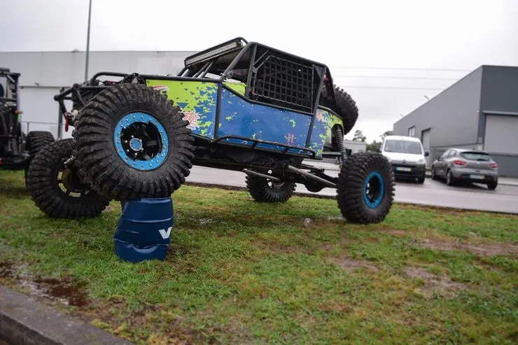 A person in a workshop disassembles mechanical parts, including various metal gears and shafts laid out on a table.
