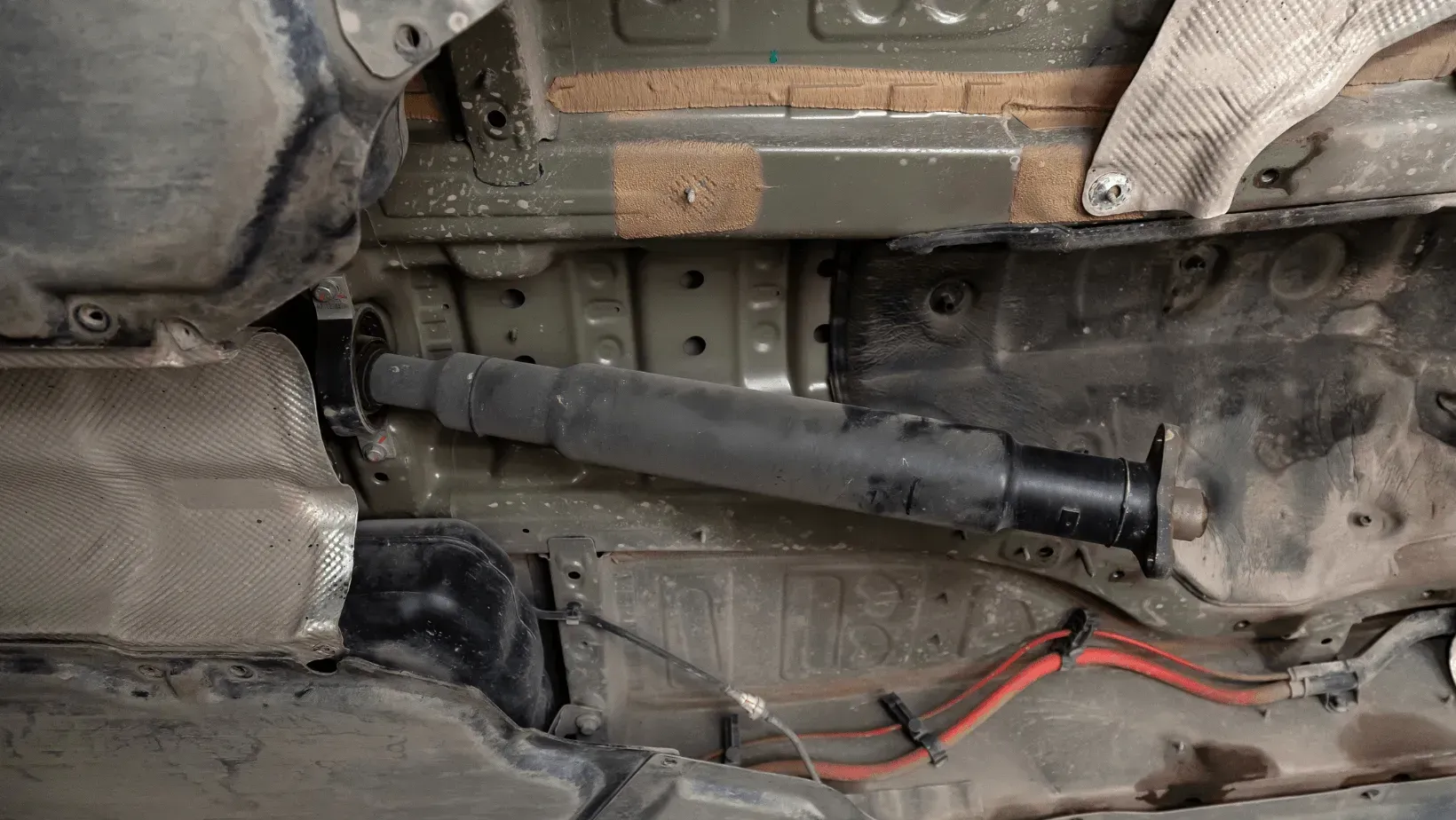 A person's hands holding metal gear components at a workbench filled with automotive parts.