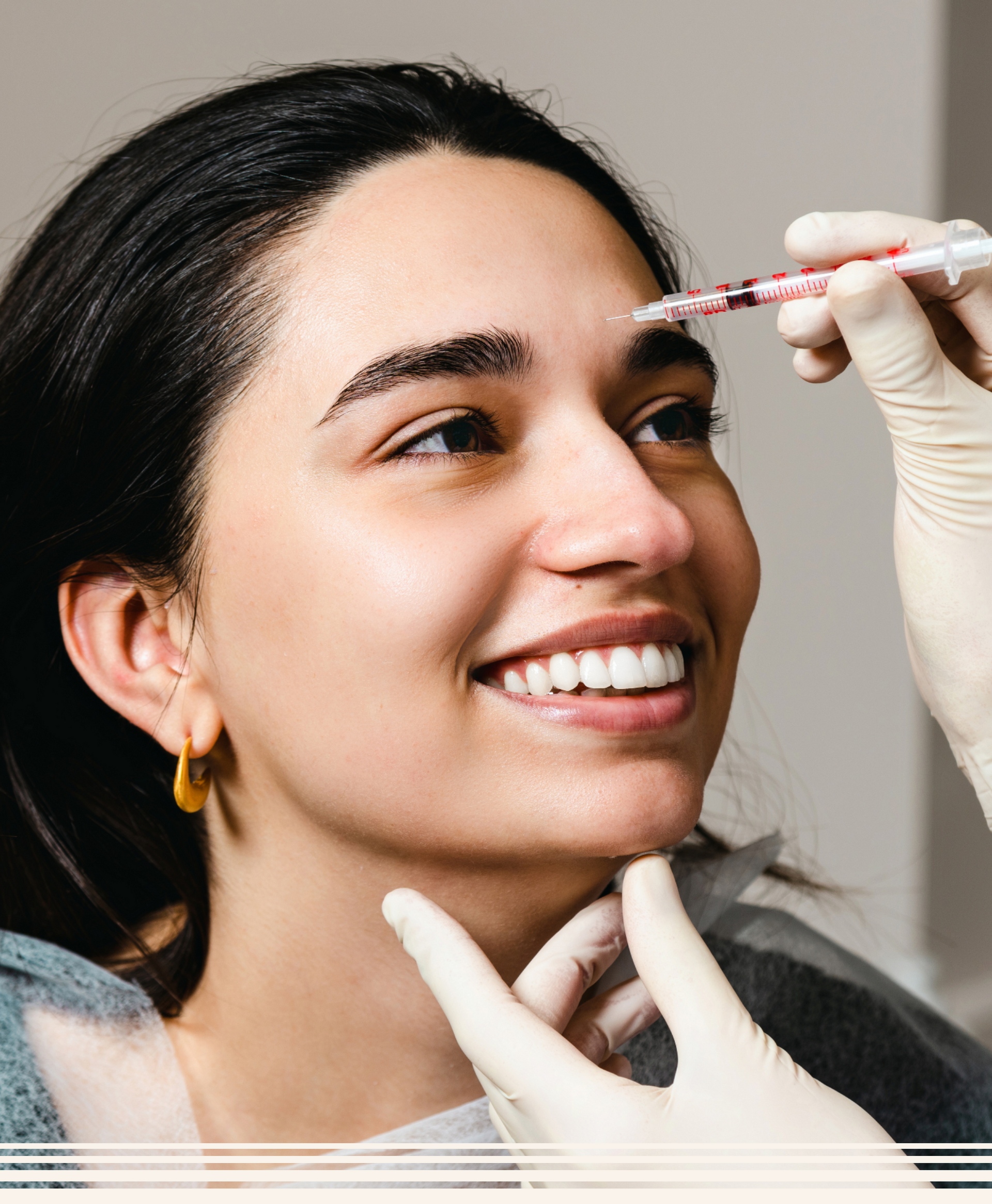 Eine Frau lächelt, während sie eine Botox-Injektion ins Gesicht bekommt