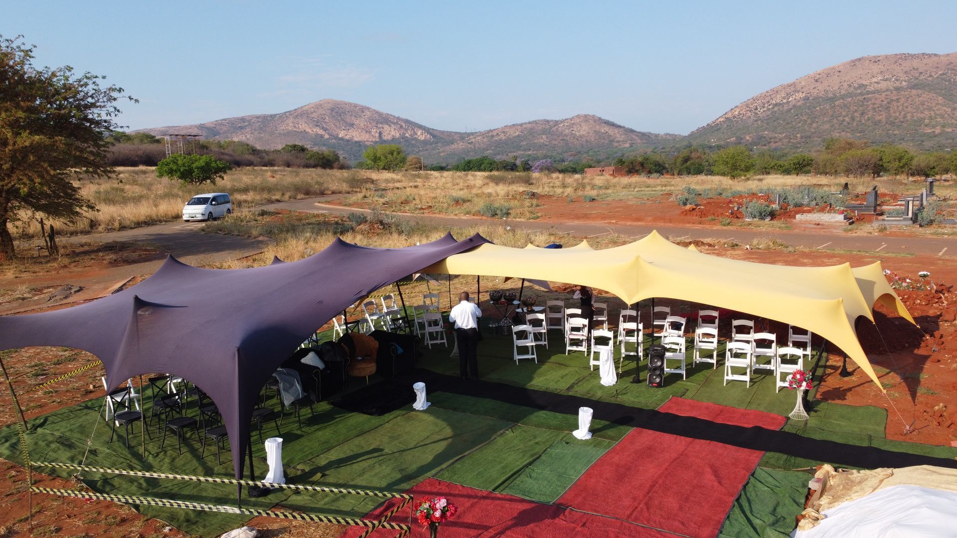 Two stretch tents with seating in a field, mountains in the background.