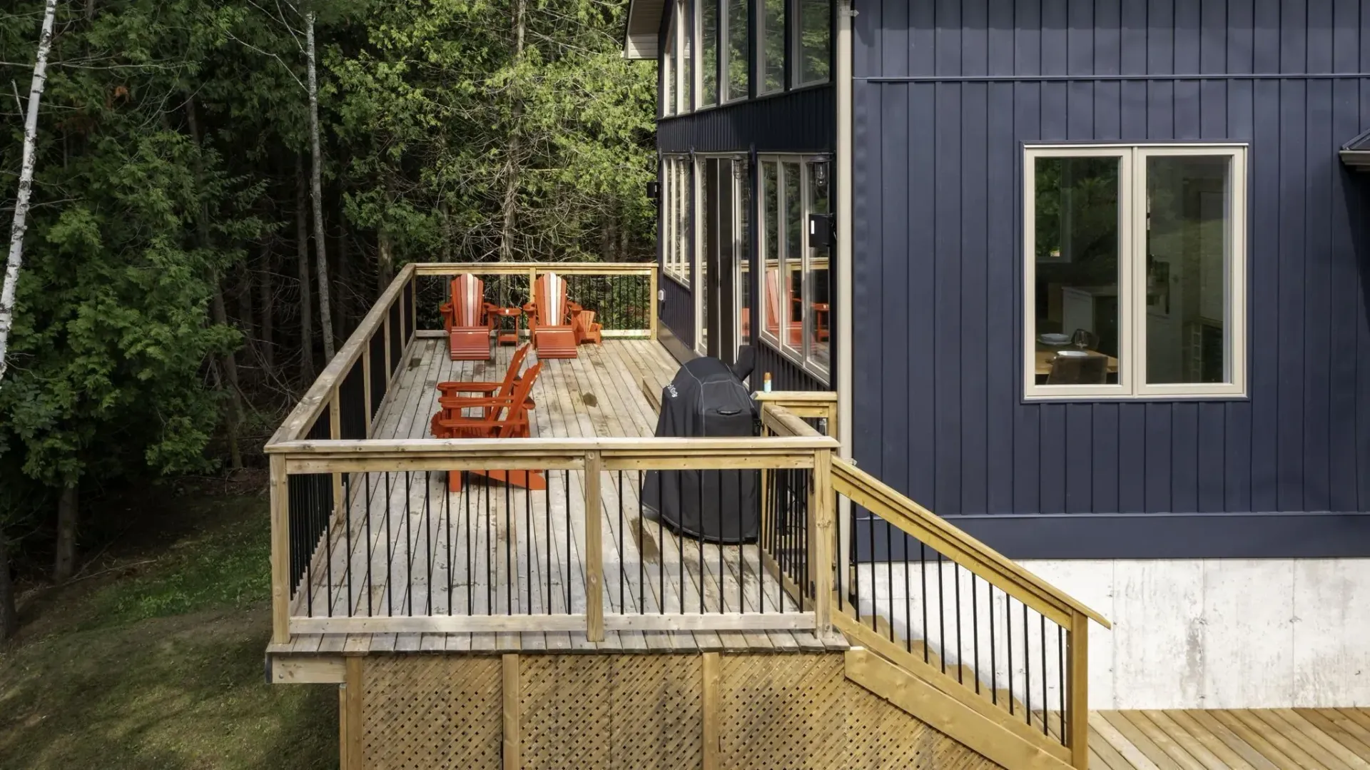 A blue house with a wooden deck and stairs in front of it.