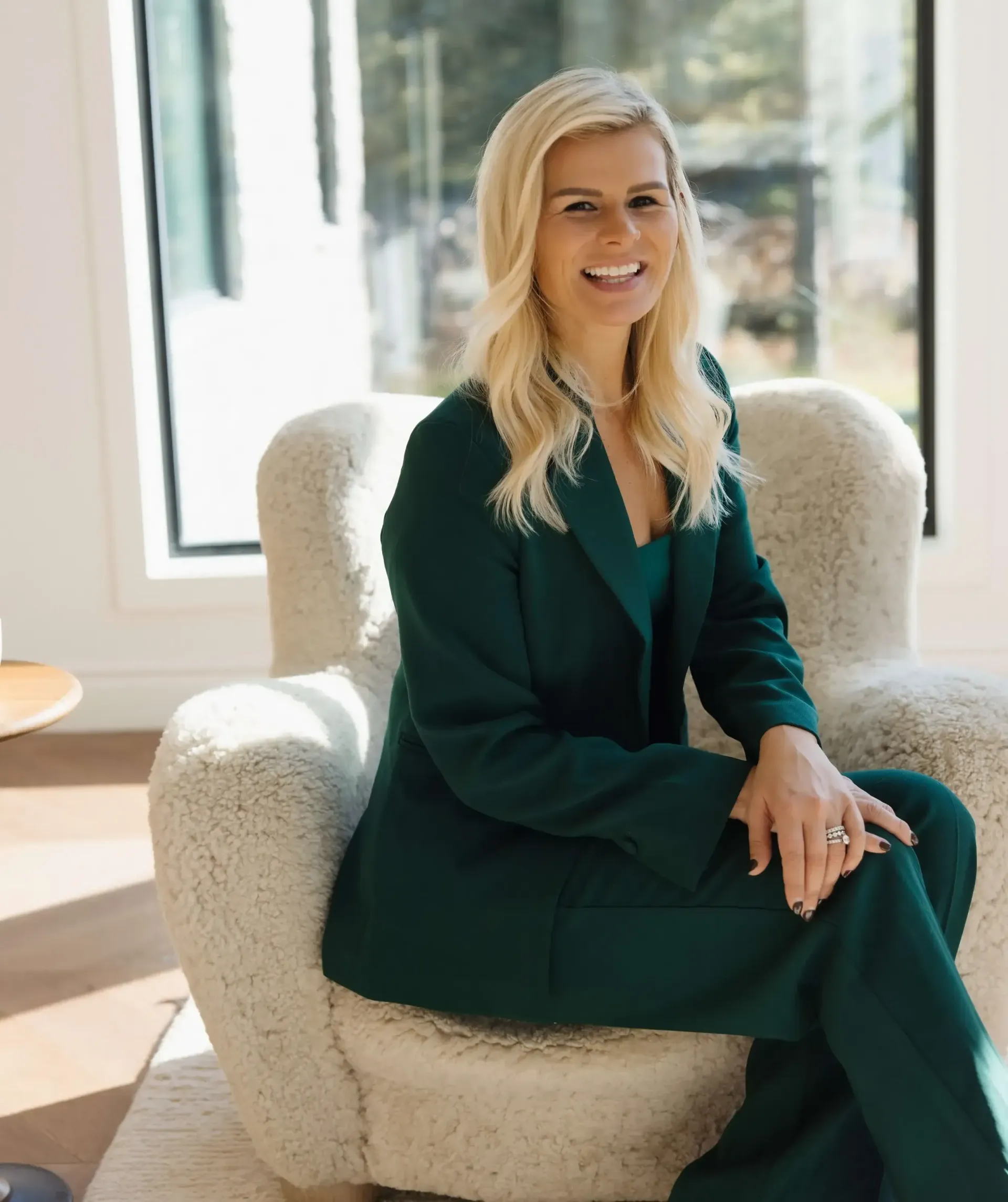 A woman in a green suit is sitting in a chair.