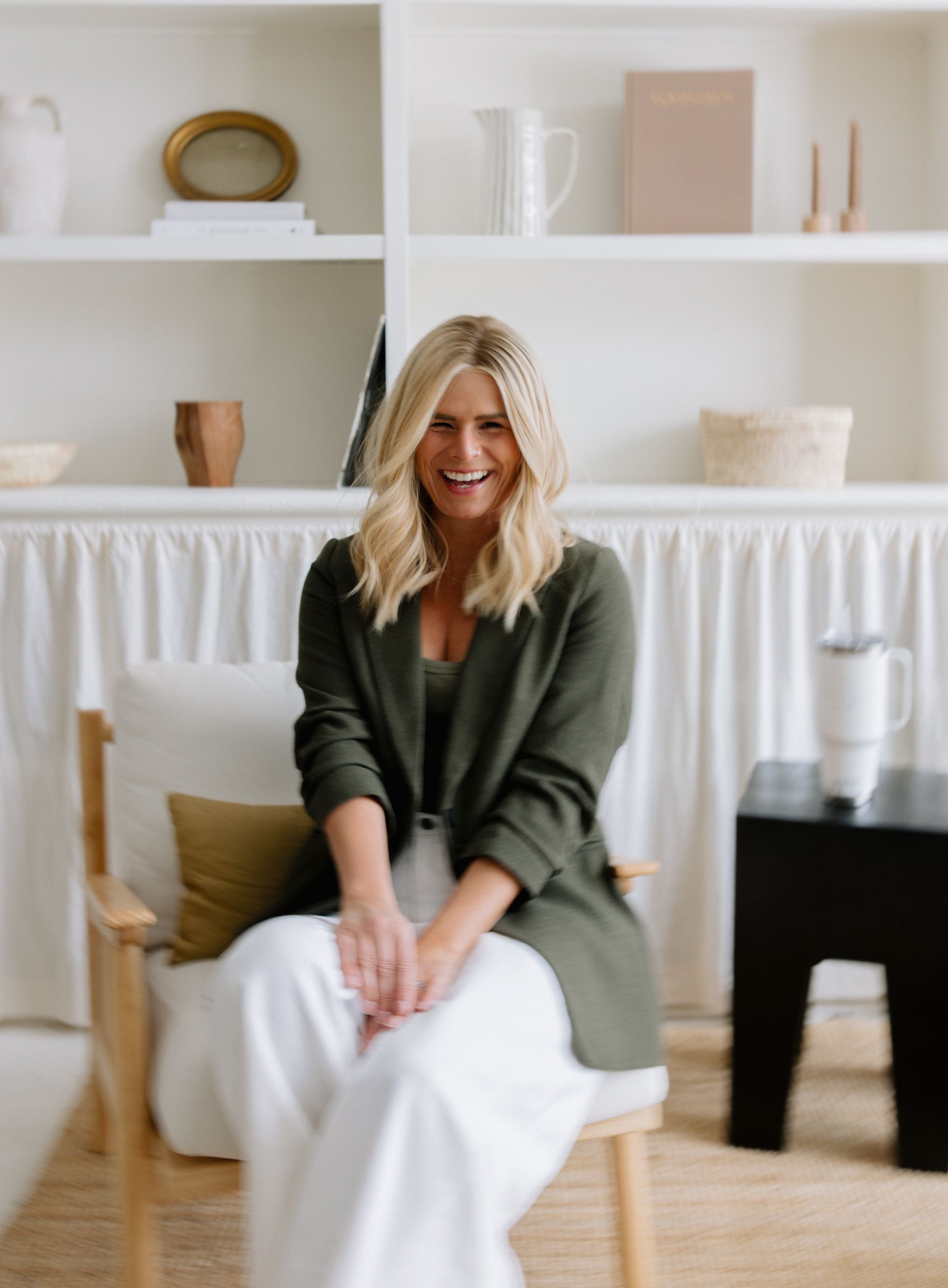 A woman is standing in a kitchen holding a vase of flowers.