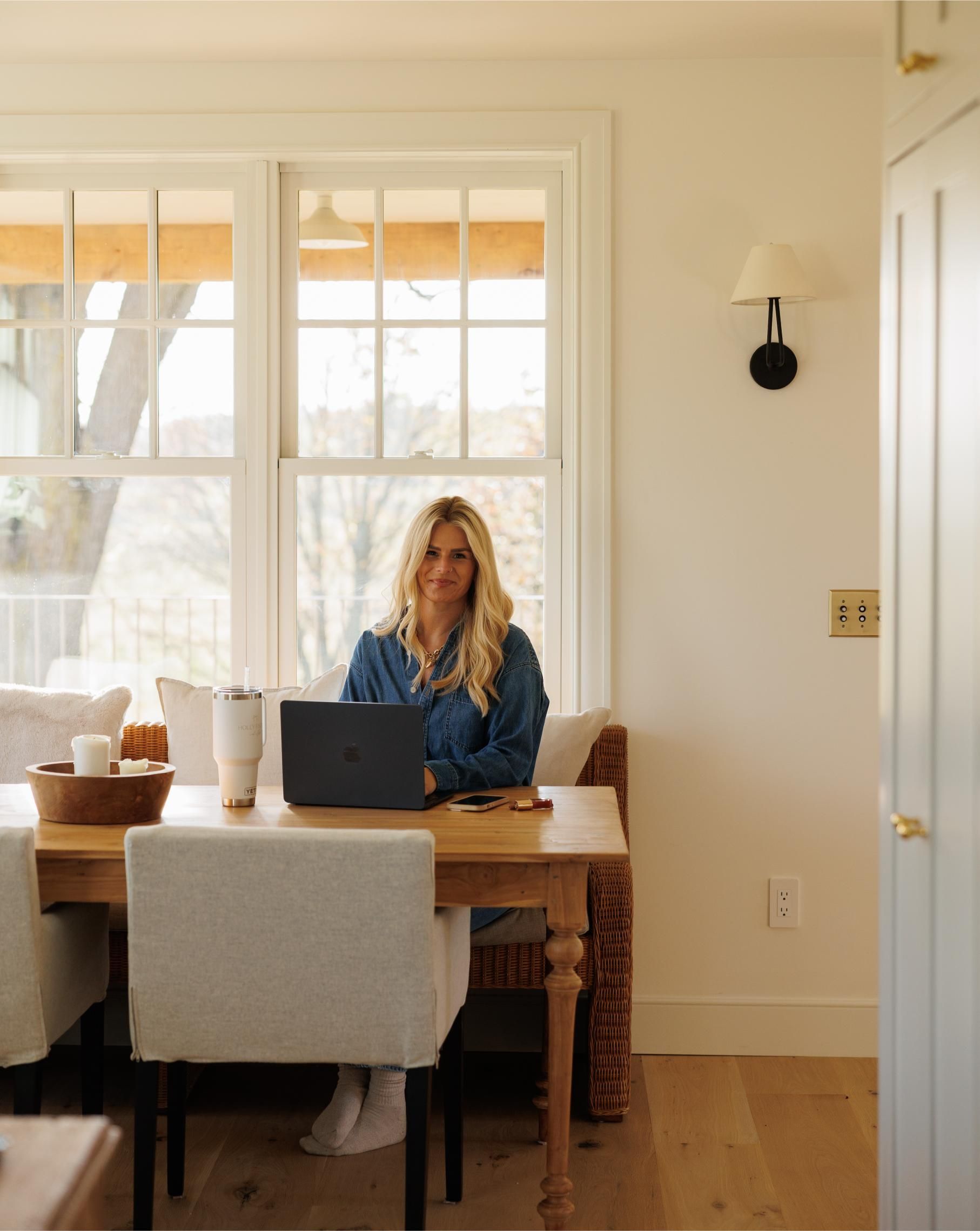A woman in a green suit is standing in front of a white curtain.
