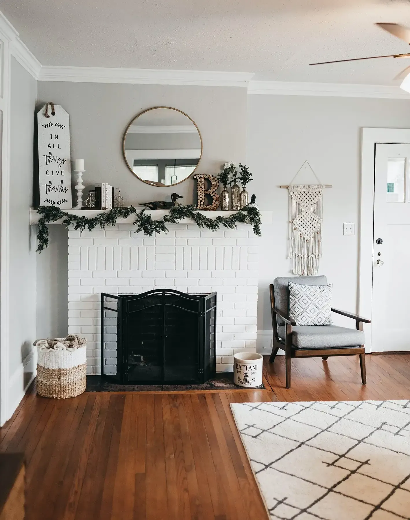 A living room with a fireplace , chair , rug and mirror.