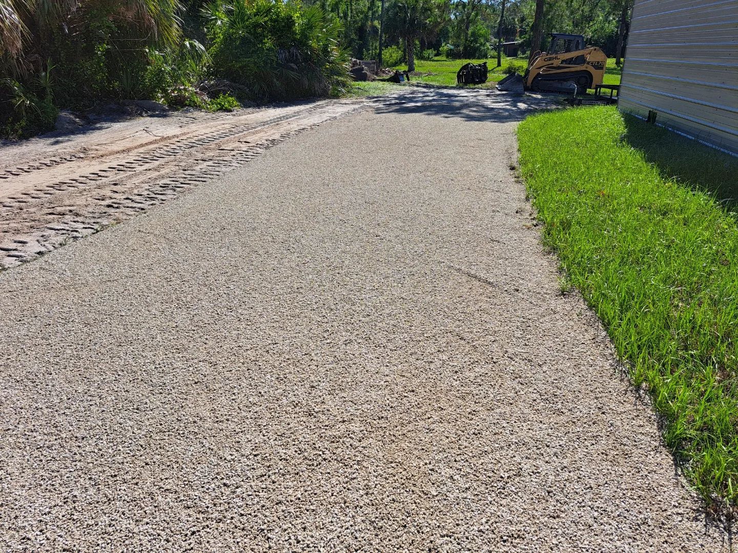 A gravel driveway is being built next to a house.