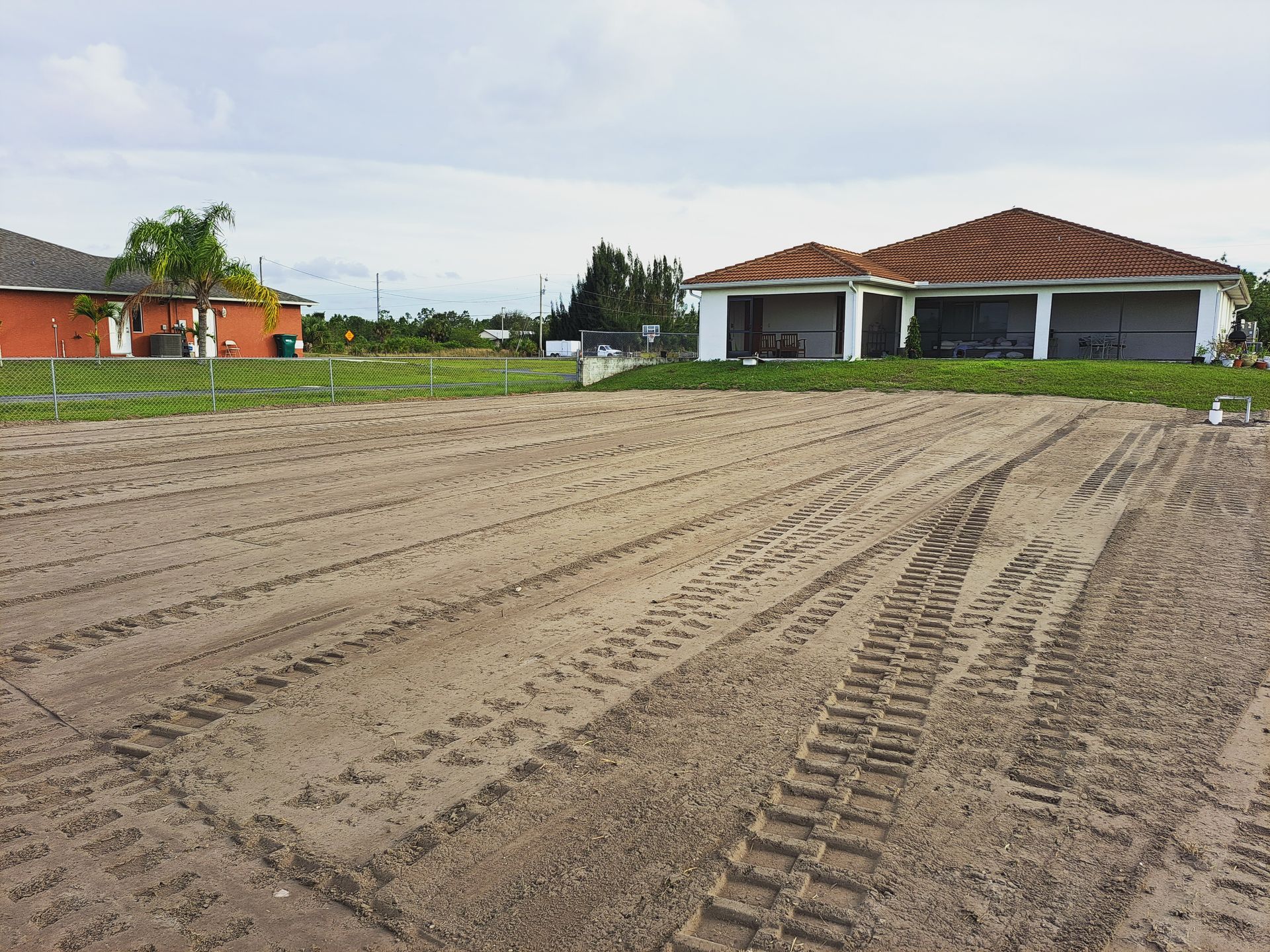 A large dirt field with a house in the background.