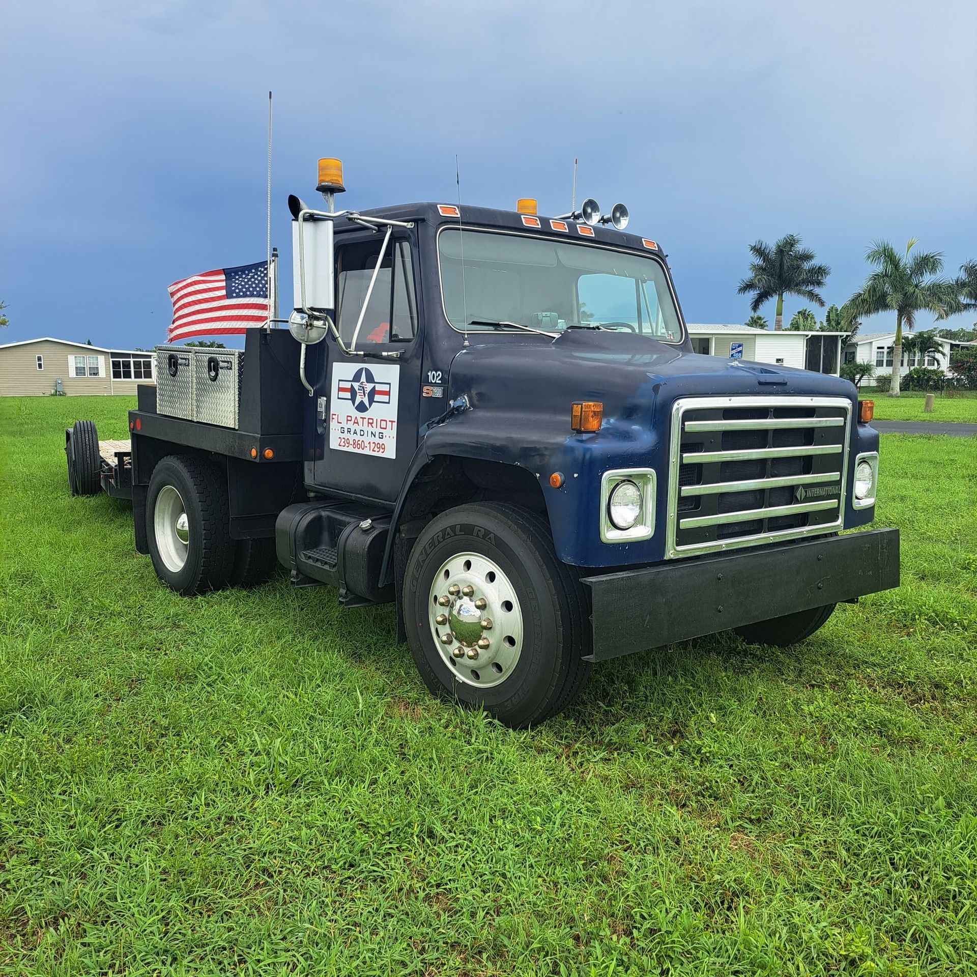 A blue truck is parked in a grassy field